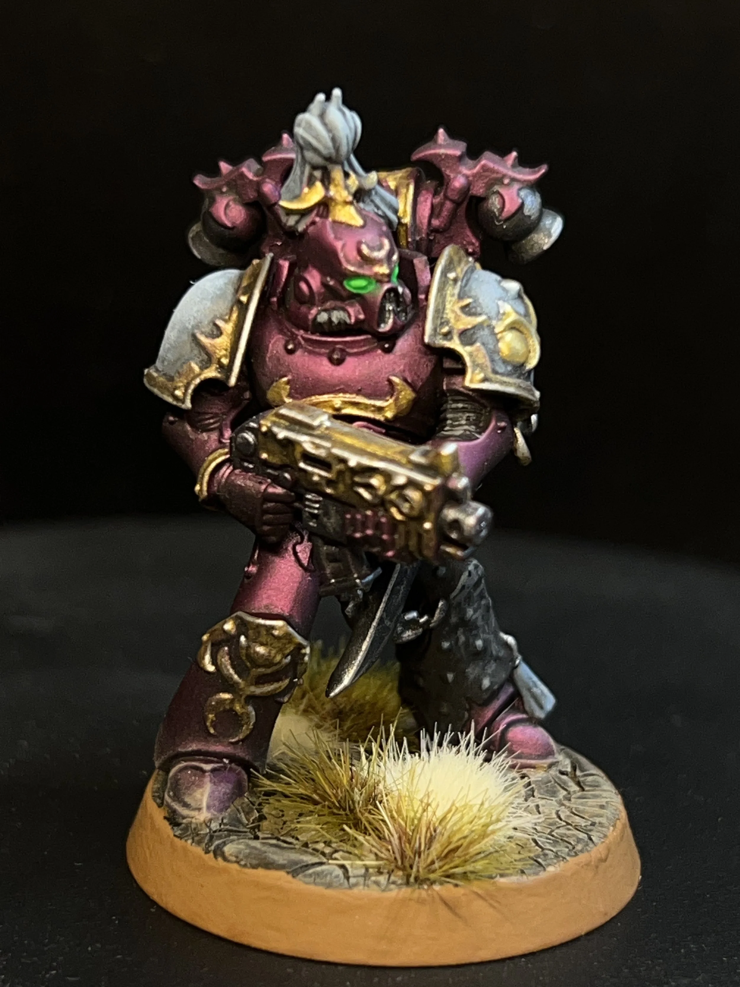 A painted miniature figurine of a fantasy warrior with armor and a gun, standing on a textured base with grass and dirt.