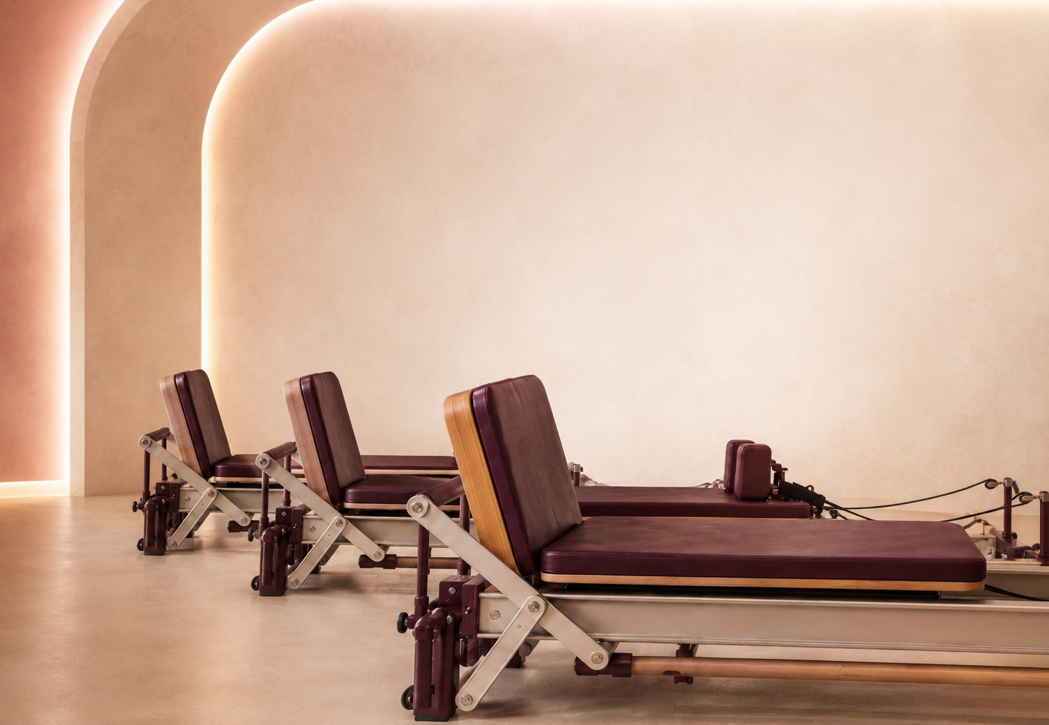 Four Pilates reformers with maroon padding.