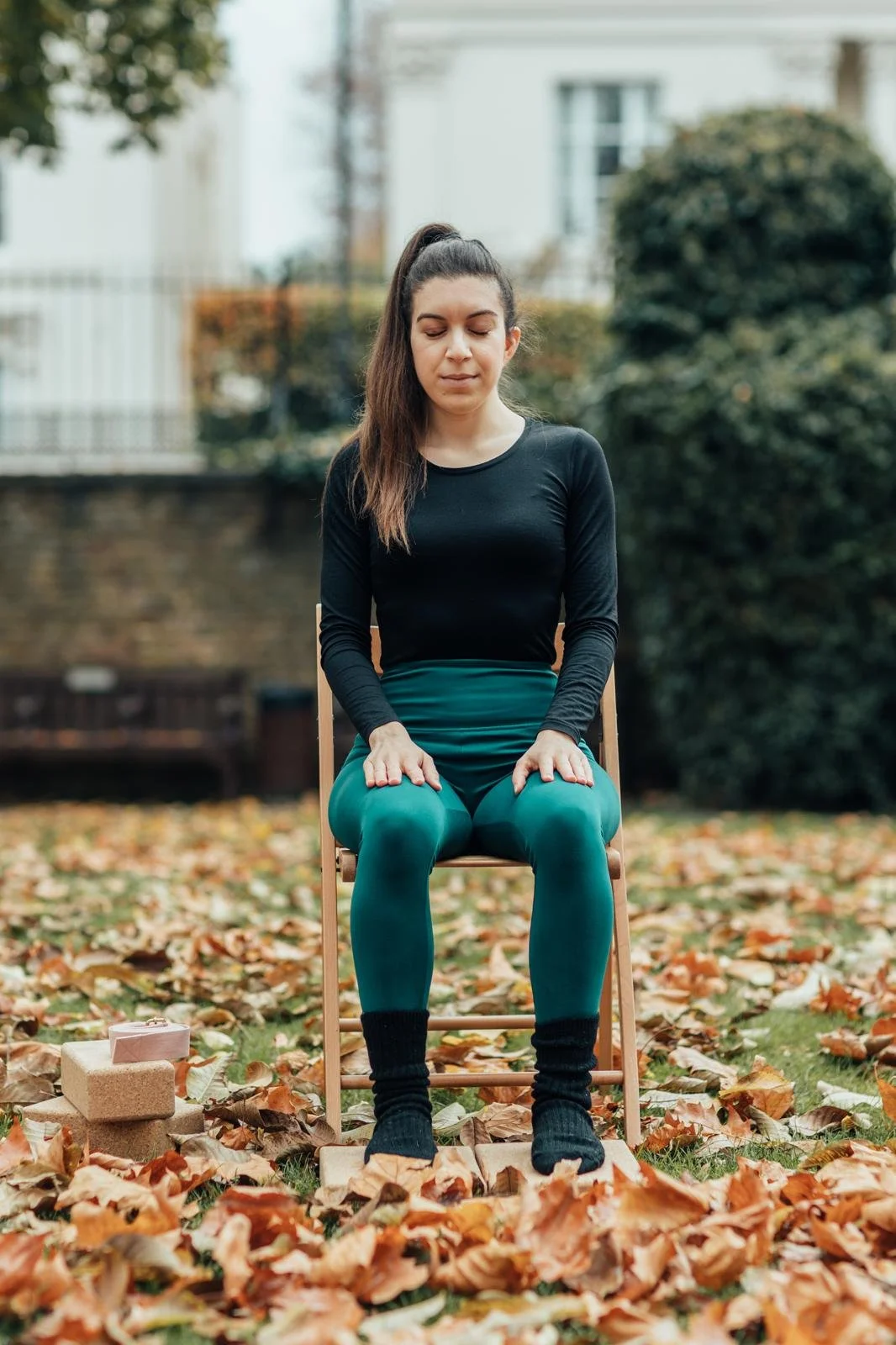A photo of Christie sitting on a chair meditating.