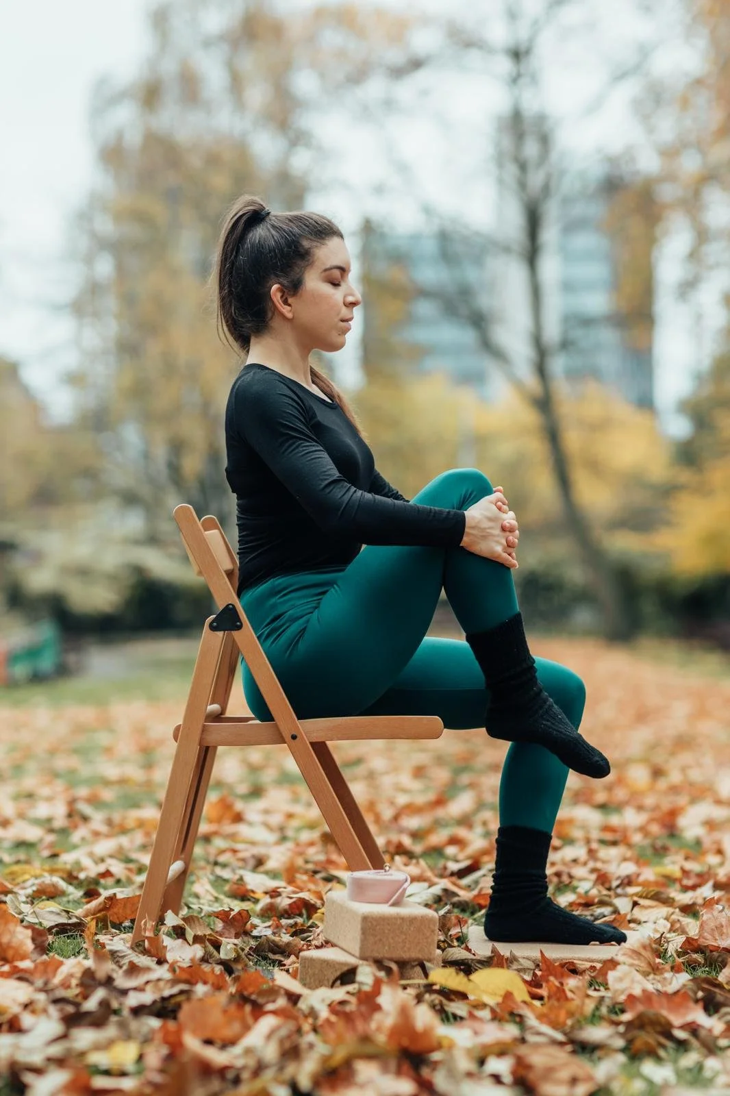 A photo of Christie practicing yoga asana sitting on a chair.