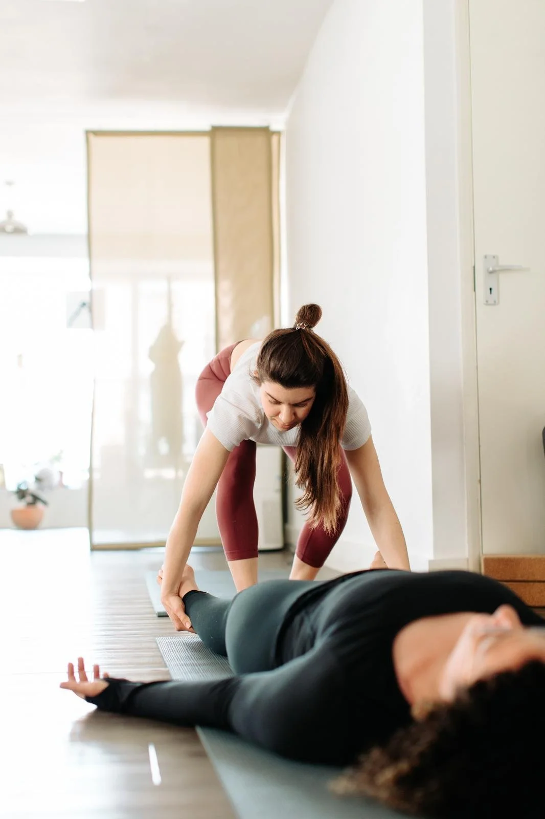 A photo of Christie assisting a student in savasana.