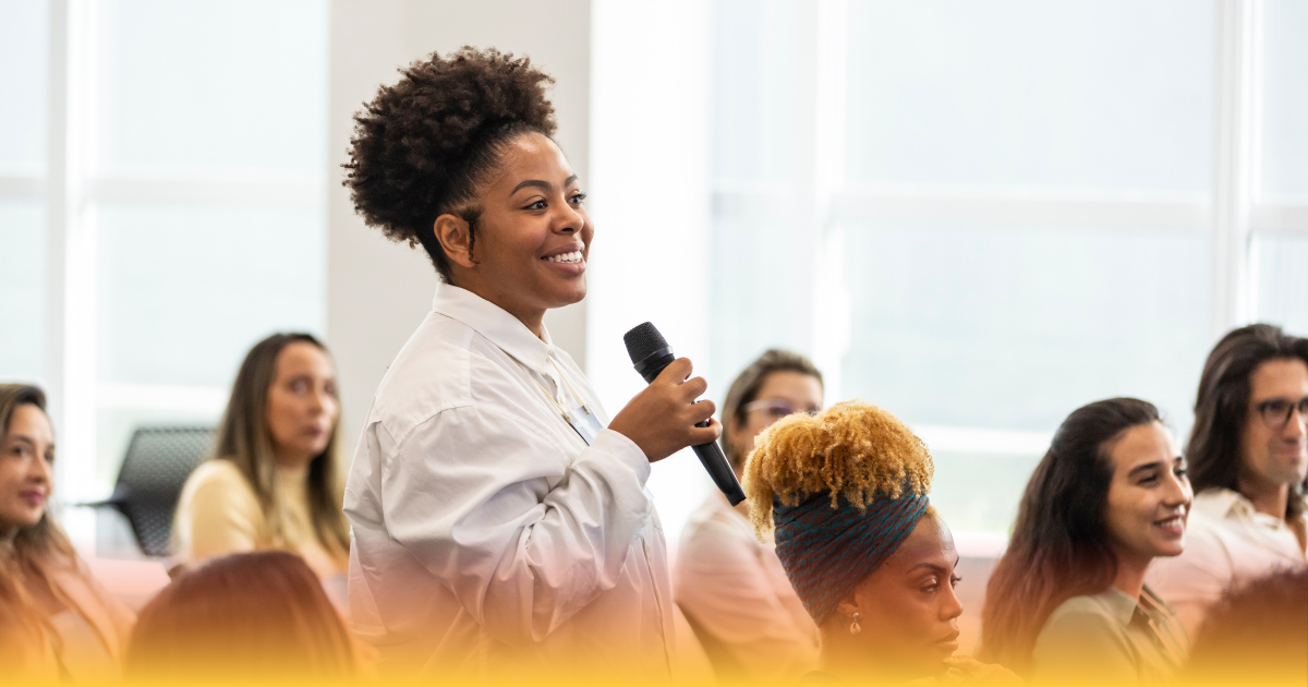 Woman speaking into a microphone during a group discussion with audience members