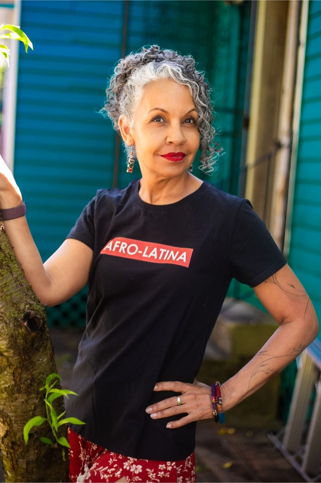 Dr. Michelle Ramos standing outdoors in New Orleans wearing an Afro-Latina shirt and smiling