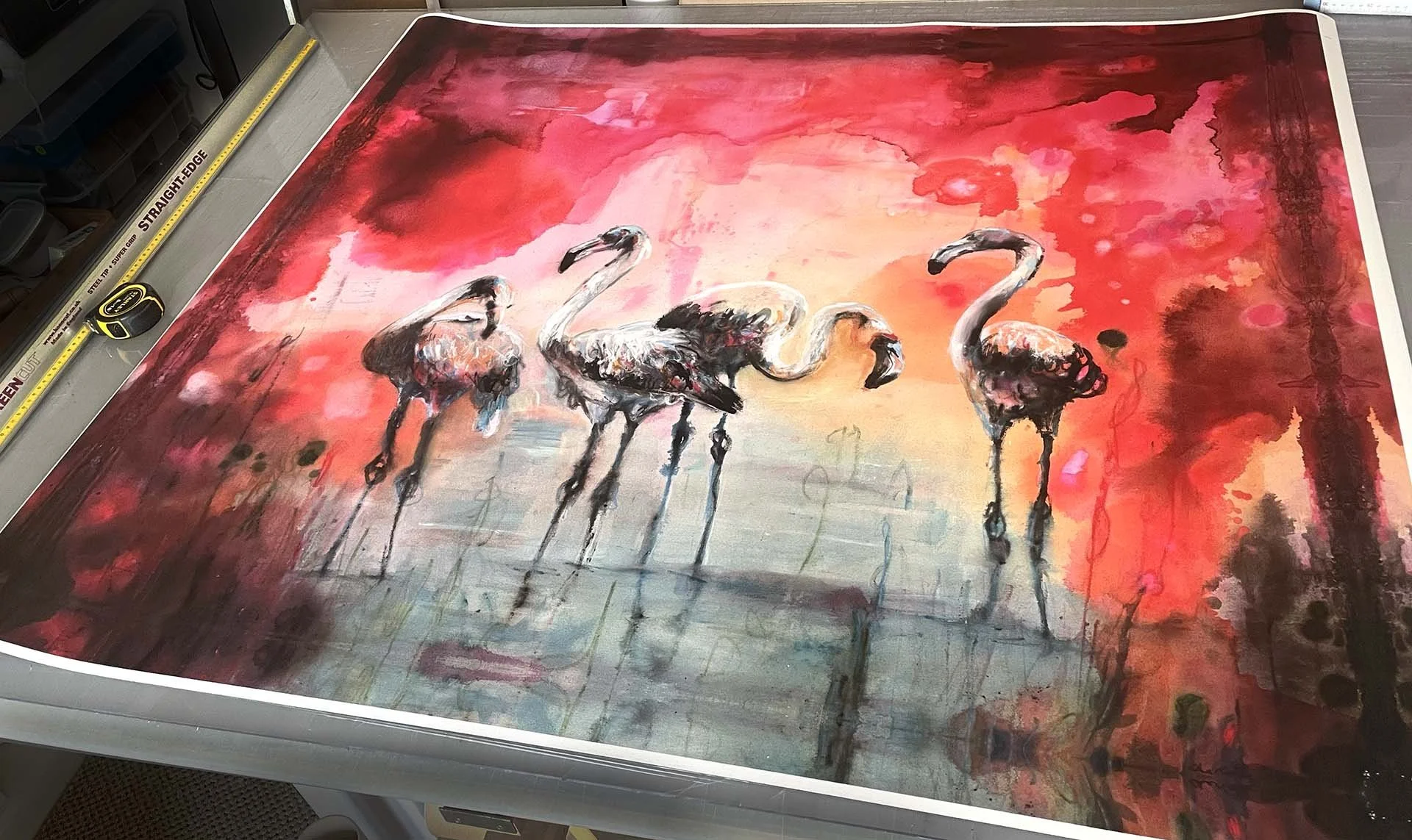 Painting of four flamingos standing in water against a bright, abstract red and pink background.