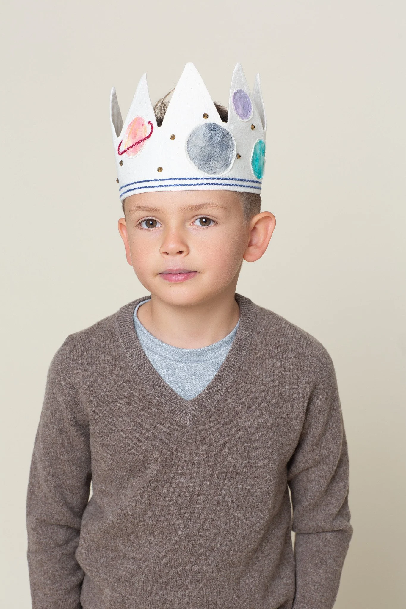 A young boy wearing an illustrated space-themed birthday crown during a milestone birthday photos studio session at Poppie Portraits in Madrona, Seattle.  