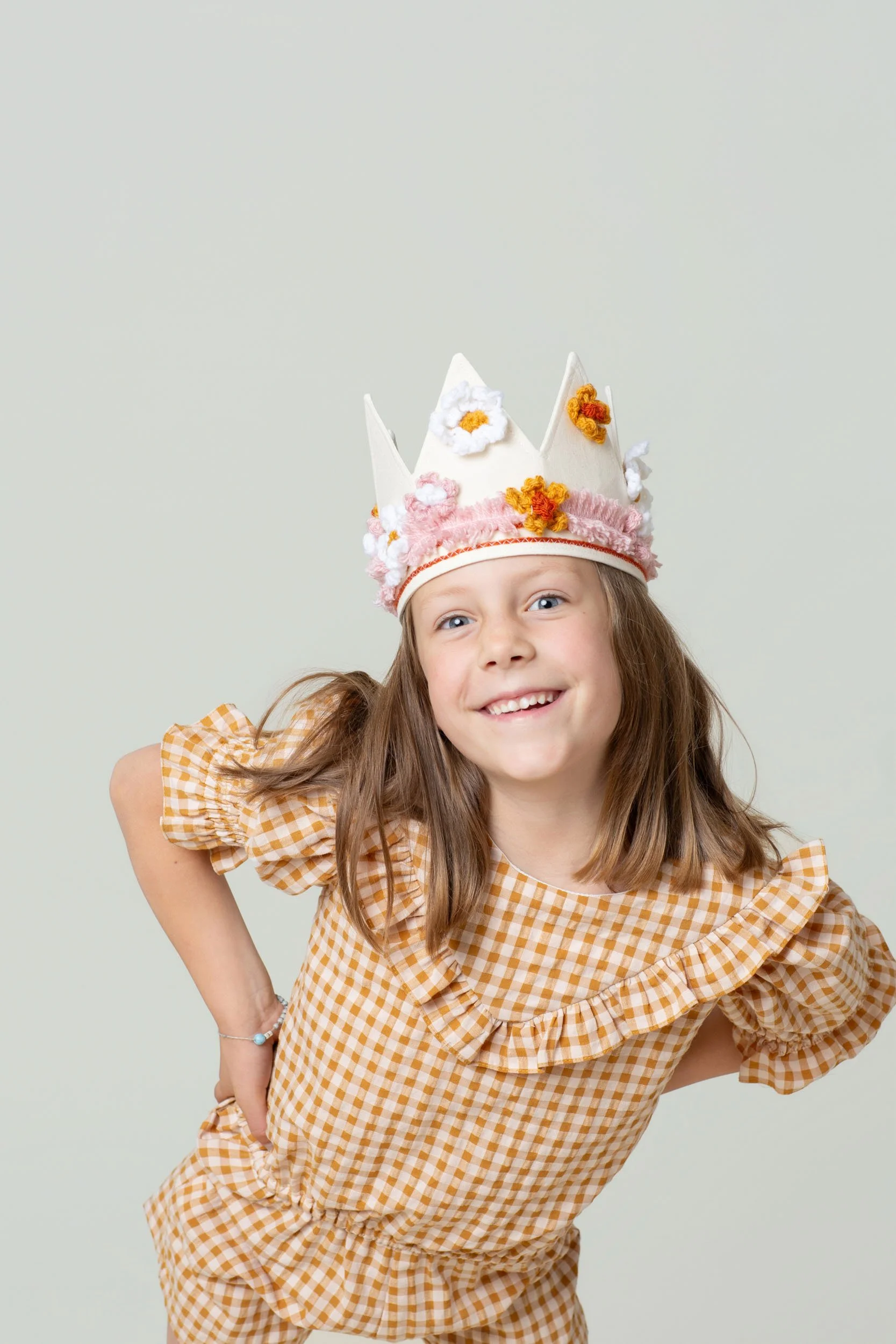 Girl in a gingham romper wearing a handmade birthday crown
