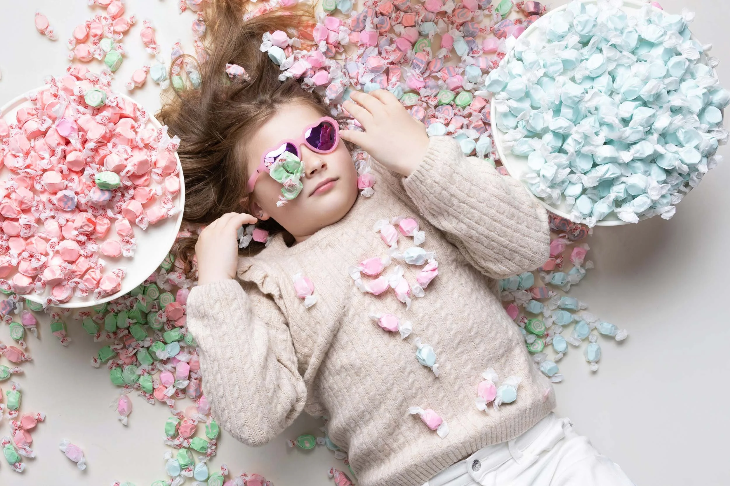 Girl reclining on the floor surrounded by taffy on cake plates
