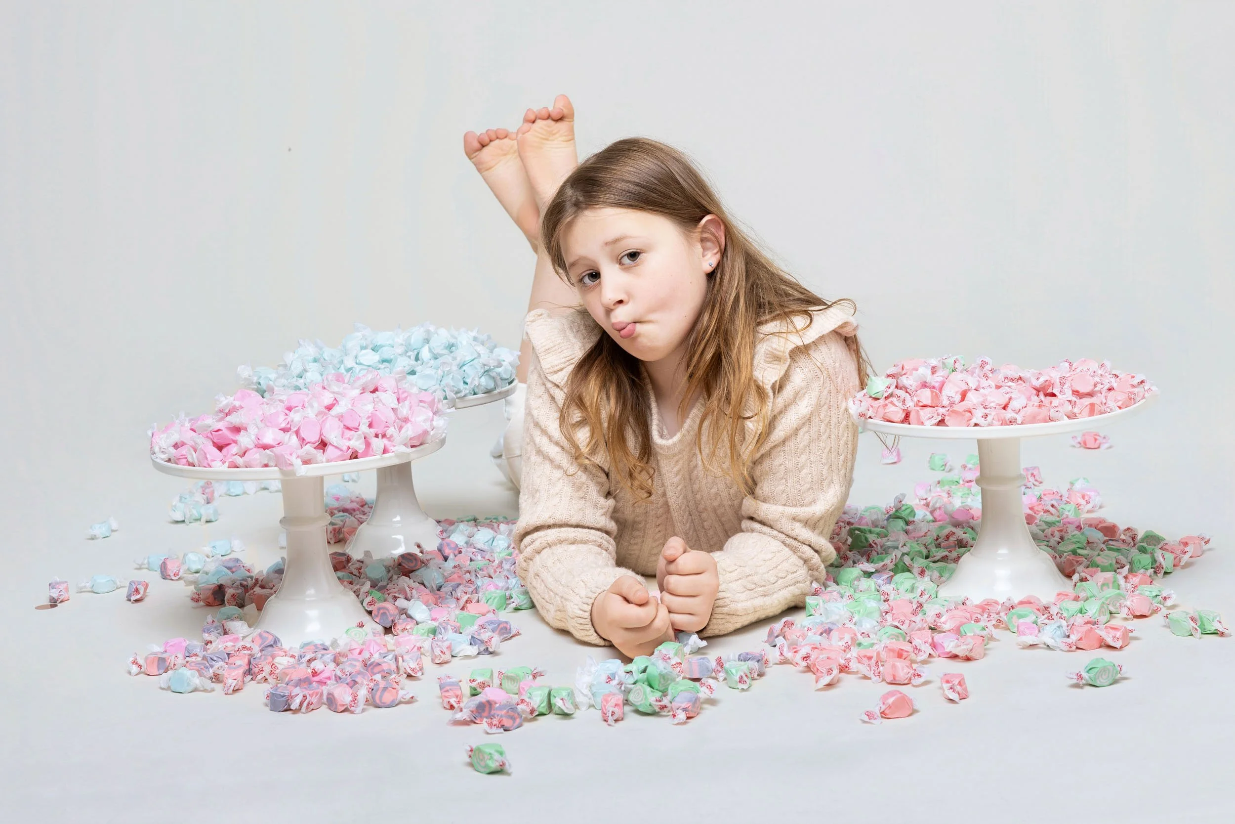 Girl lying among scattered sprinkles and cupcakes, hands framing her face