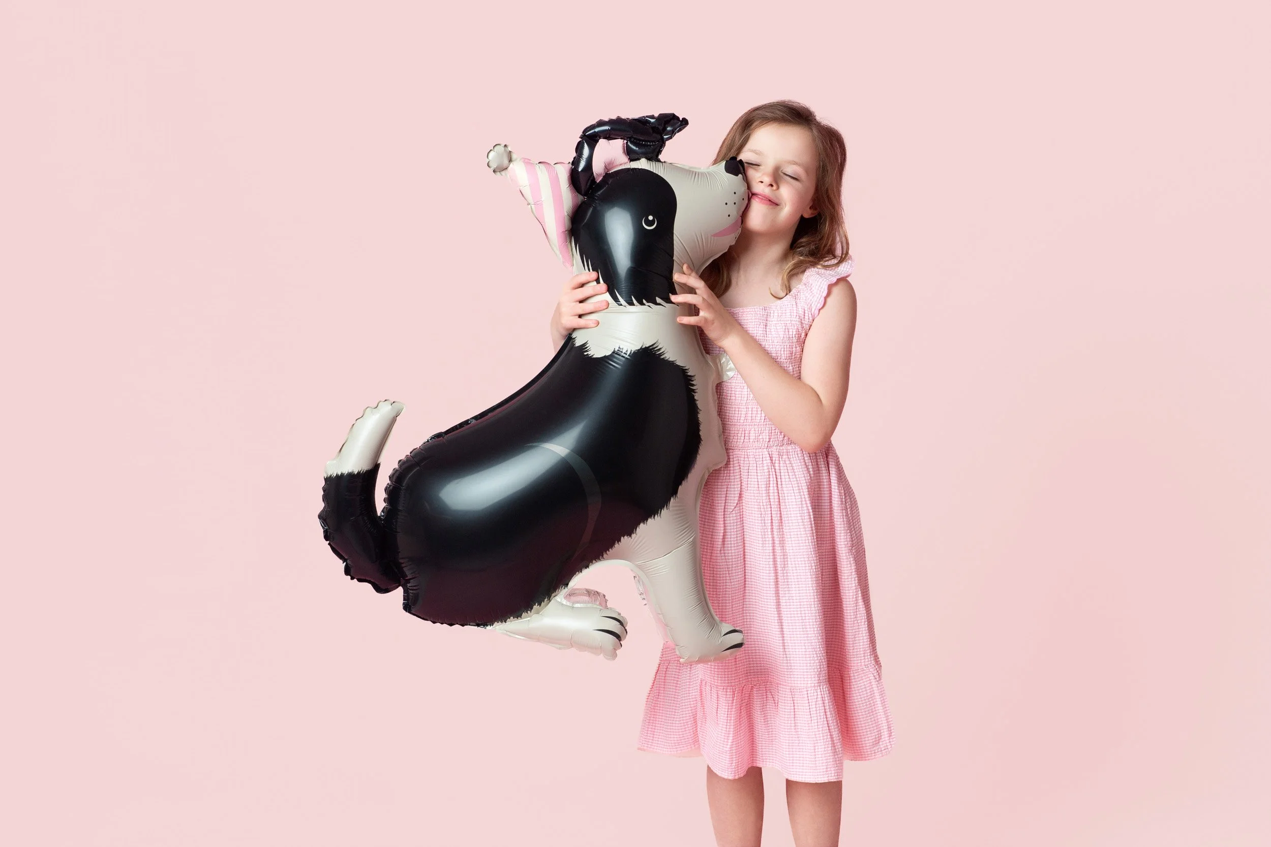 Girl in a pink dress with a black dog-shaped foil balloon