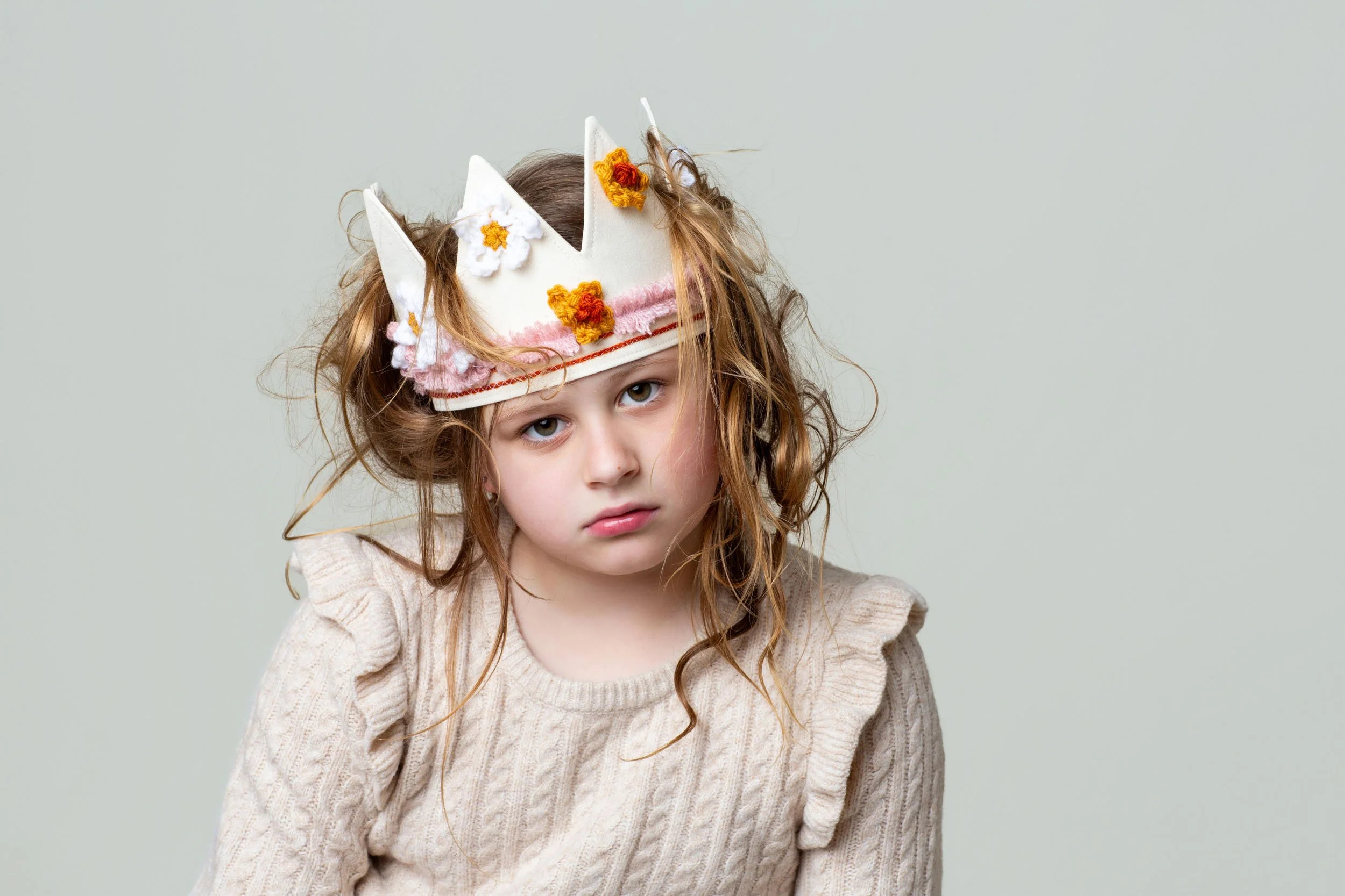 A young girl posing with a handcrafted floral party crown during a milestone birthday photos session at Poppie Portraits in Seattle.