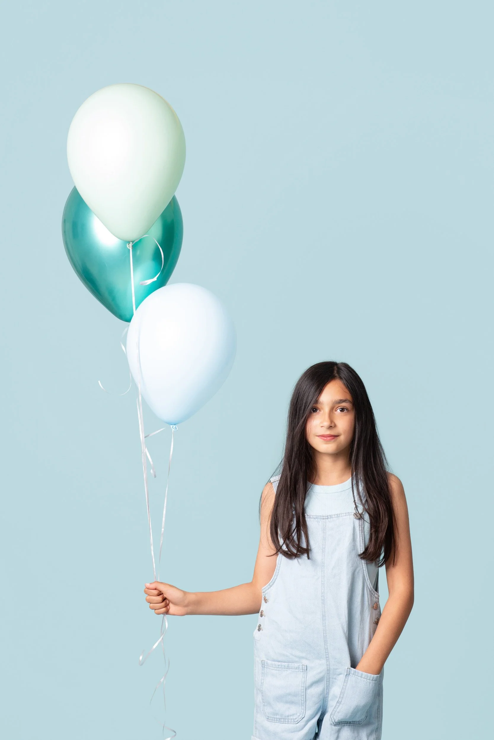 Girl with long dark hair holding a swirl lollipop on a blue background