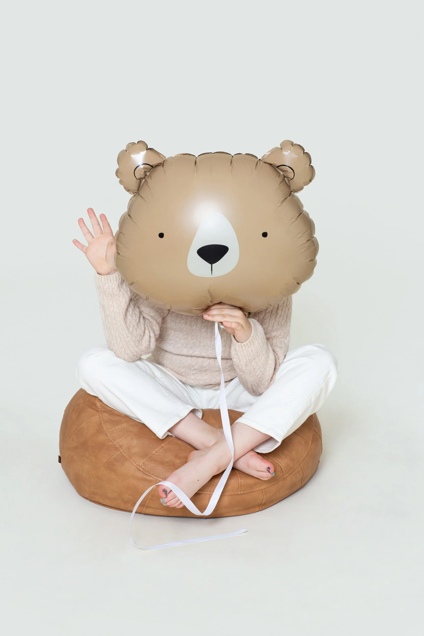Child seated with an oversized teddy bear balloon during a birthday photoshoot at Poppie Portraits in Seattle. 