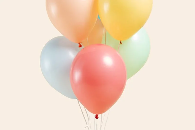 A custom pastel balloon bouquet display featuring coral, mint, yellow, and blue birthday balloons at Poppie Portraits in Seattle.