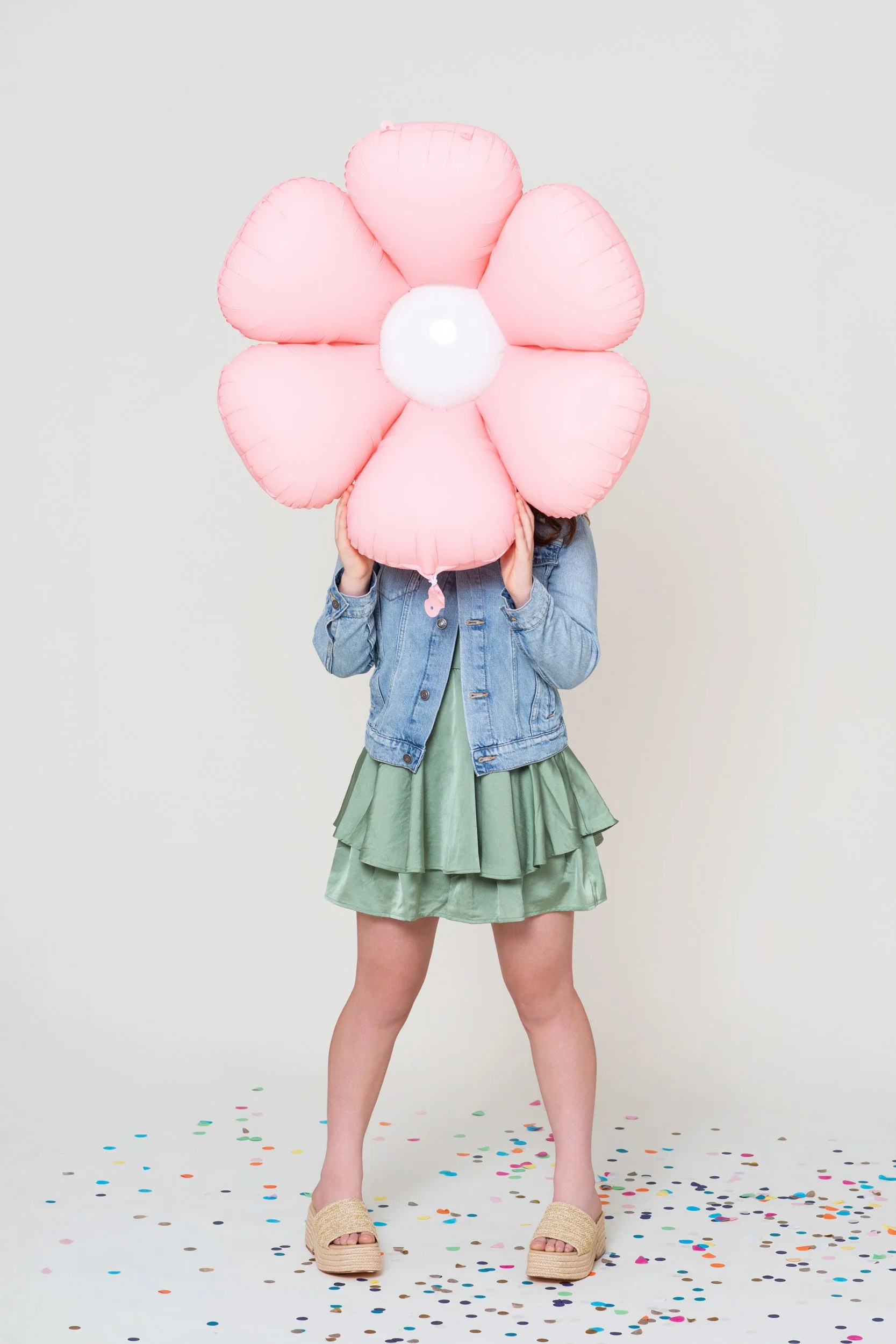 A girl holding a pink flower balloon during a kids birthday portraits session at the Poppie Portraits studio in Madrona, Seattle.  