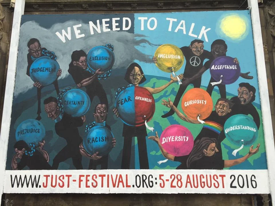 A colorful mural with diverse people holding large spheres labeled with concepts like judgment, exclusion, acceptance, fear, openness, curiosity, understanding, diversity, prejudice, racism, and certainty. The mural’s message is 'We need to talk' and