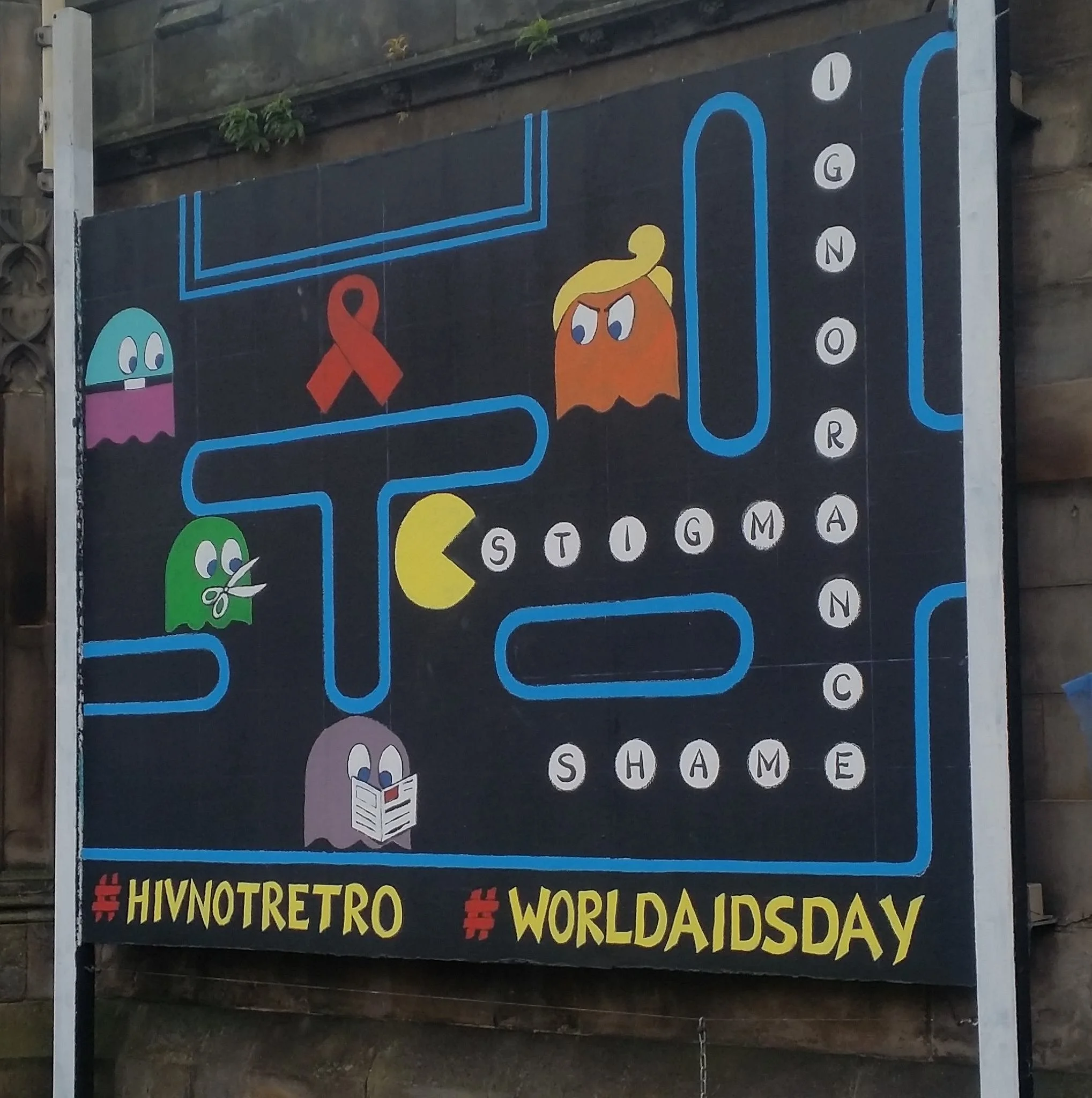 A large outdoor sign celebrating World Autism Awareness Day, featuring cartoon characters and hashtags in multiple languages, with colorful designs and text.