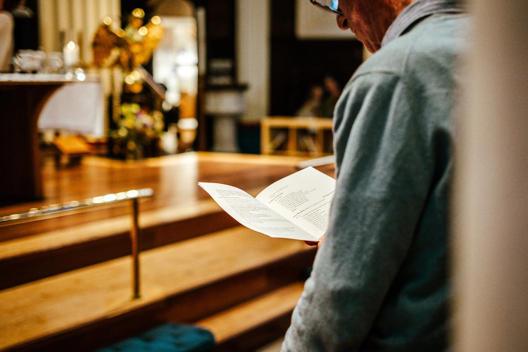 A person reading a paper in front of a piano in a cozy room with warm lighting and Christmas decorations.