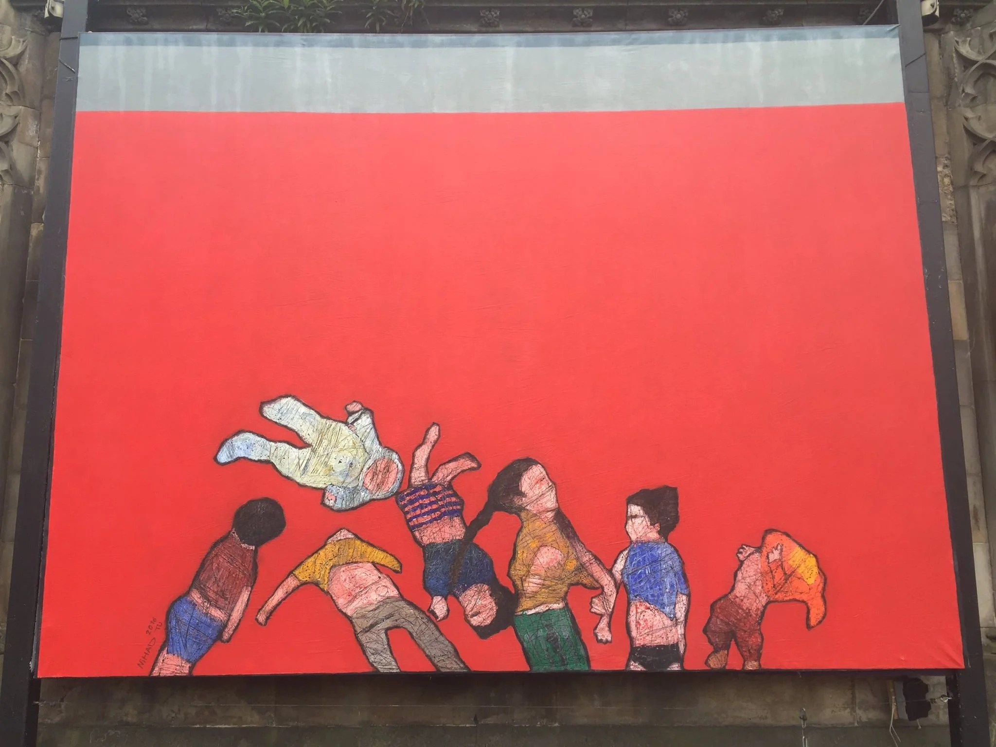 Colorful artwork on a large outdoor mural painting showing a group of children playing with a large fish, painted on a red background