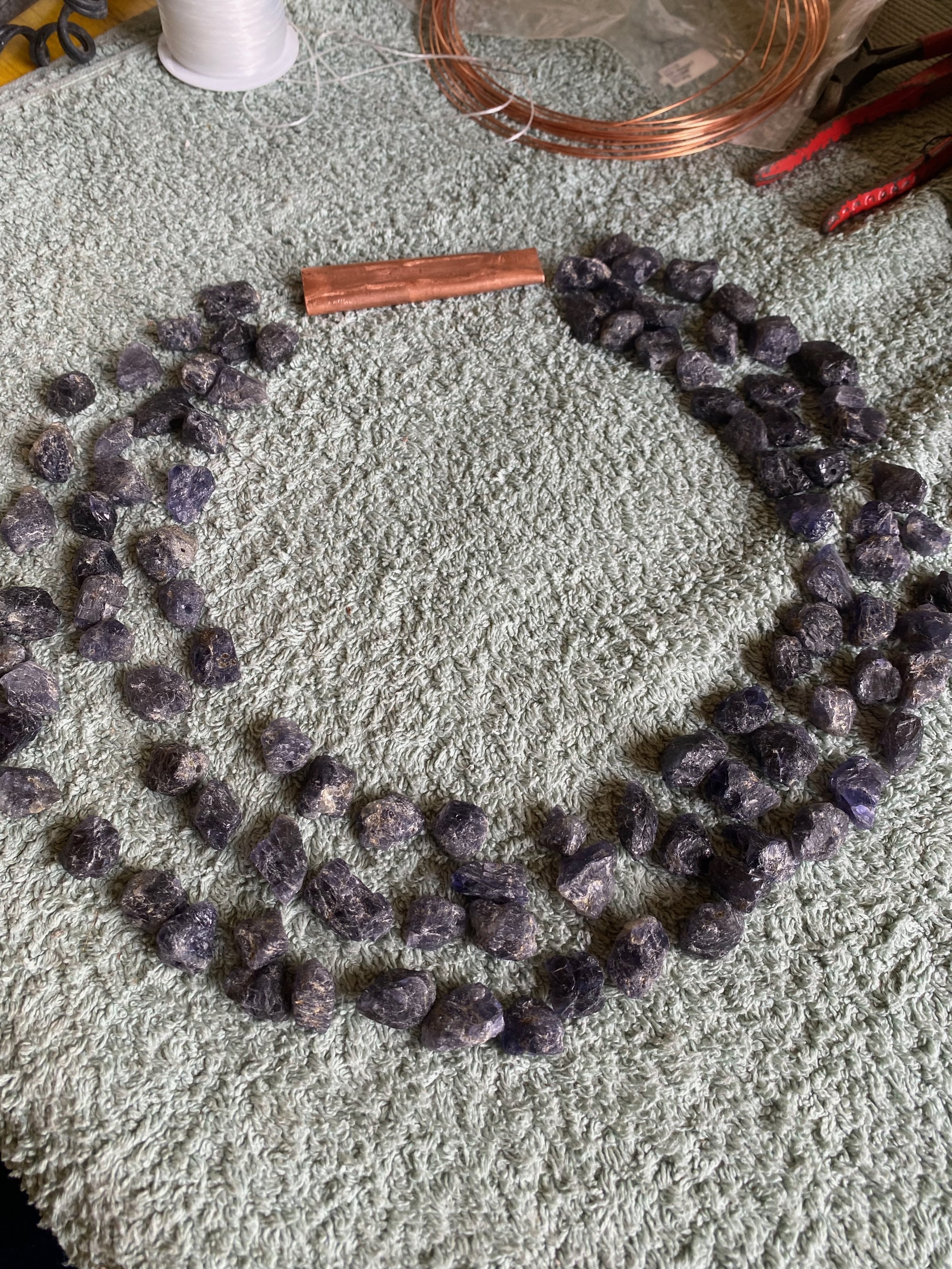 Copper wire, black rocks, and tools on a textured carpet.