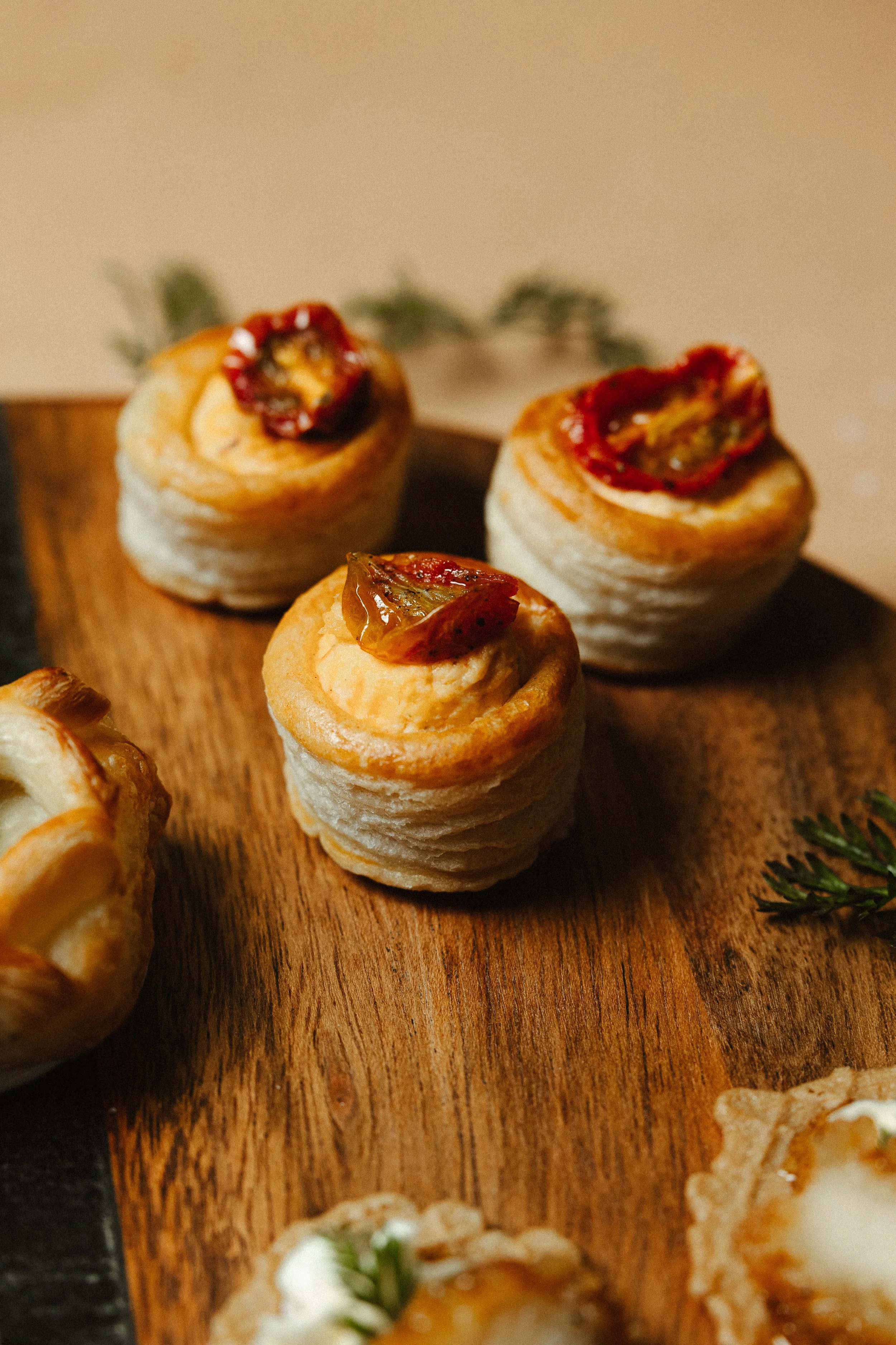Close-up of puff pastry pinwheels with sun-dried tomatoes on a wooden serving board.