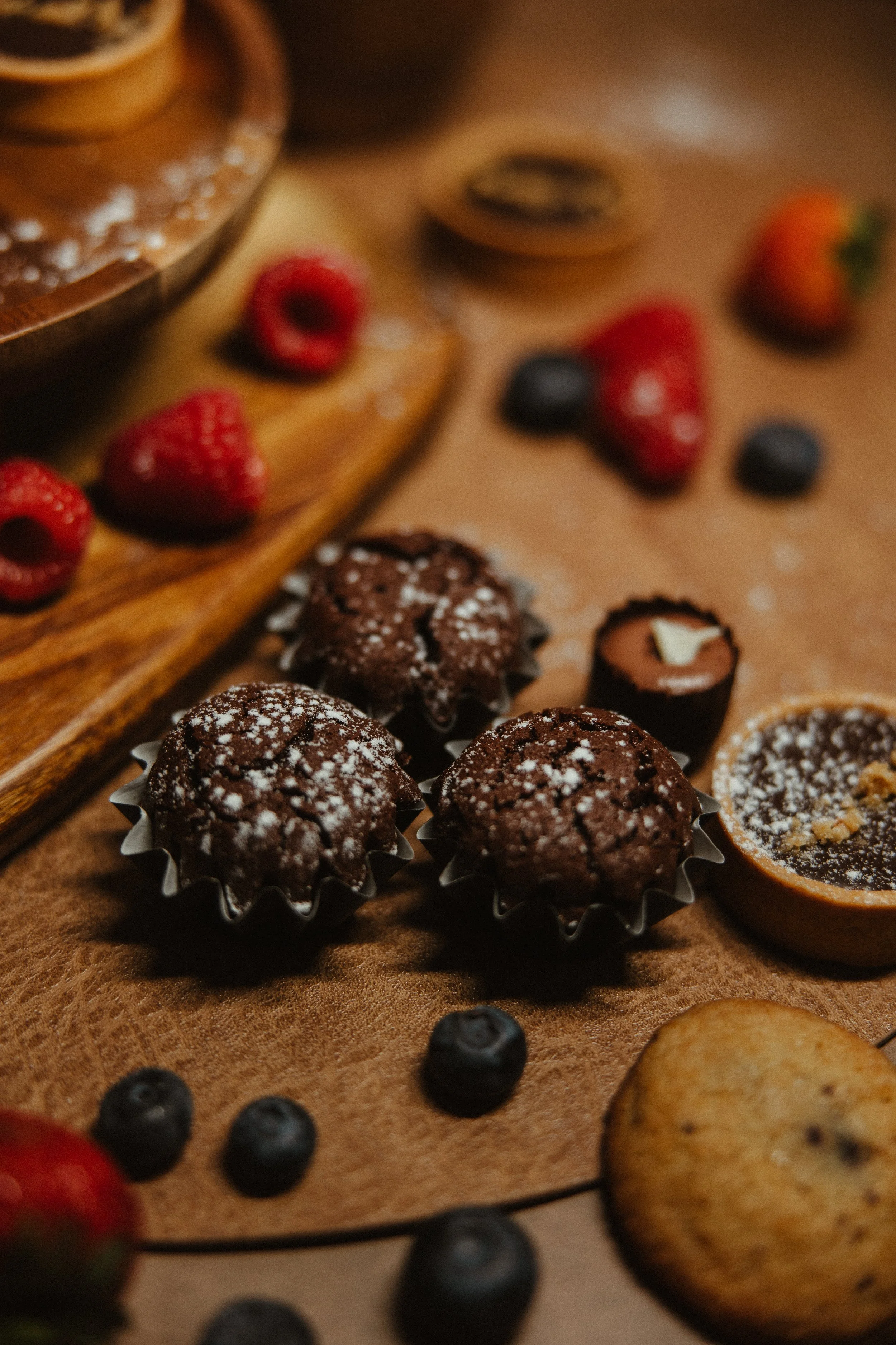 Assorted chocolates and berries on a wooden surface.
