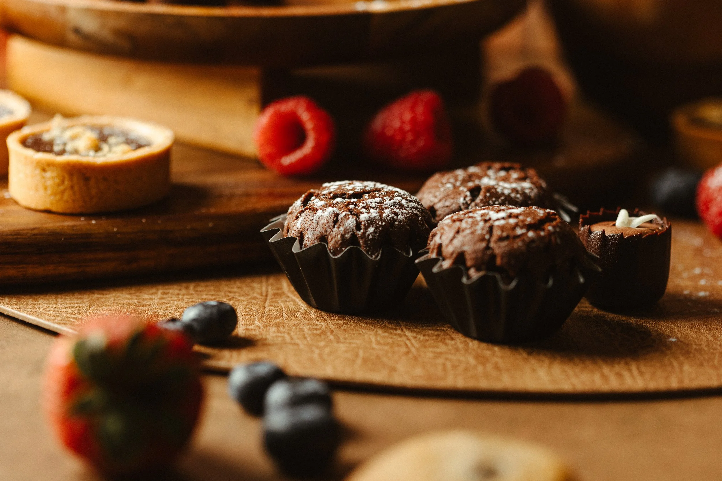 Assorted chocolates and strawberries arranged on a wooden surface with a rustic background.