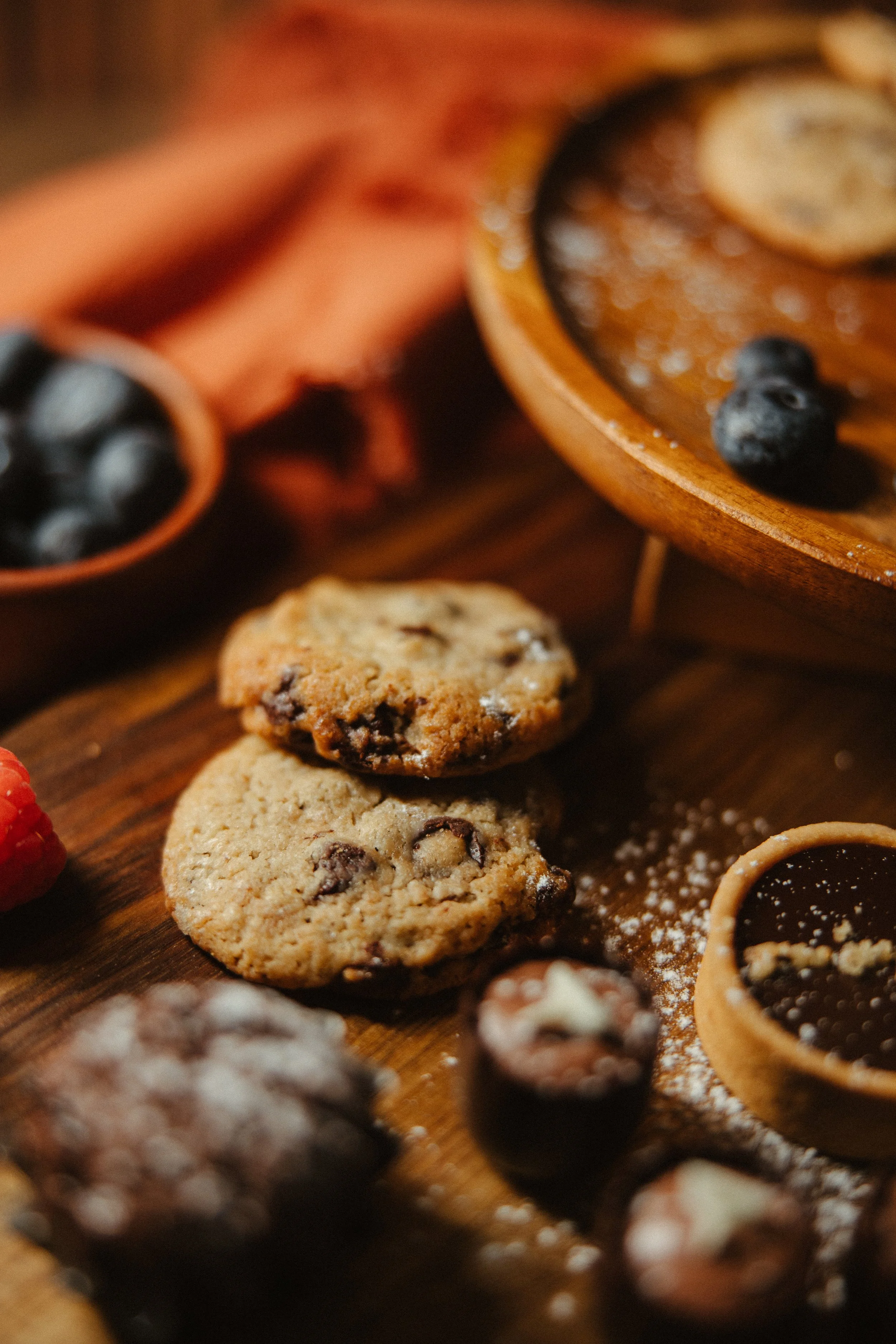 Close-up of assorted cookies and blueberries on a wooden surface, with a rustic, warm tone.
