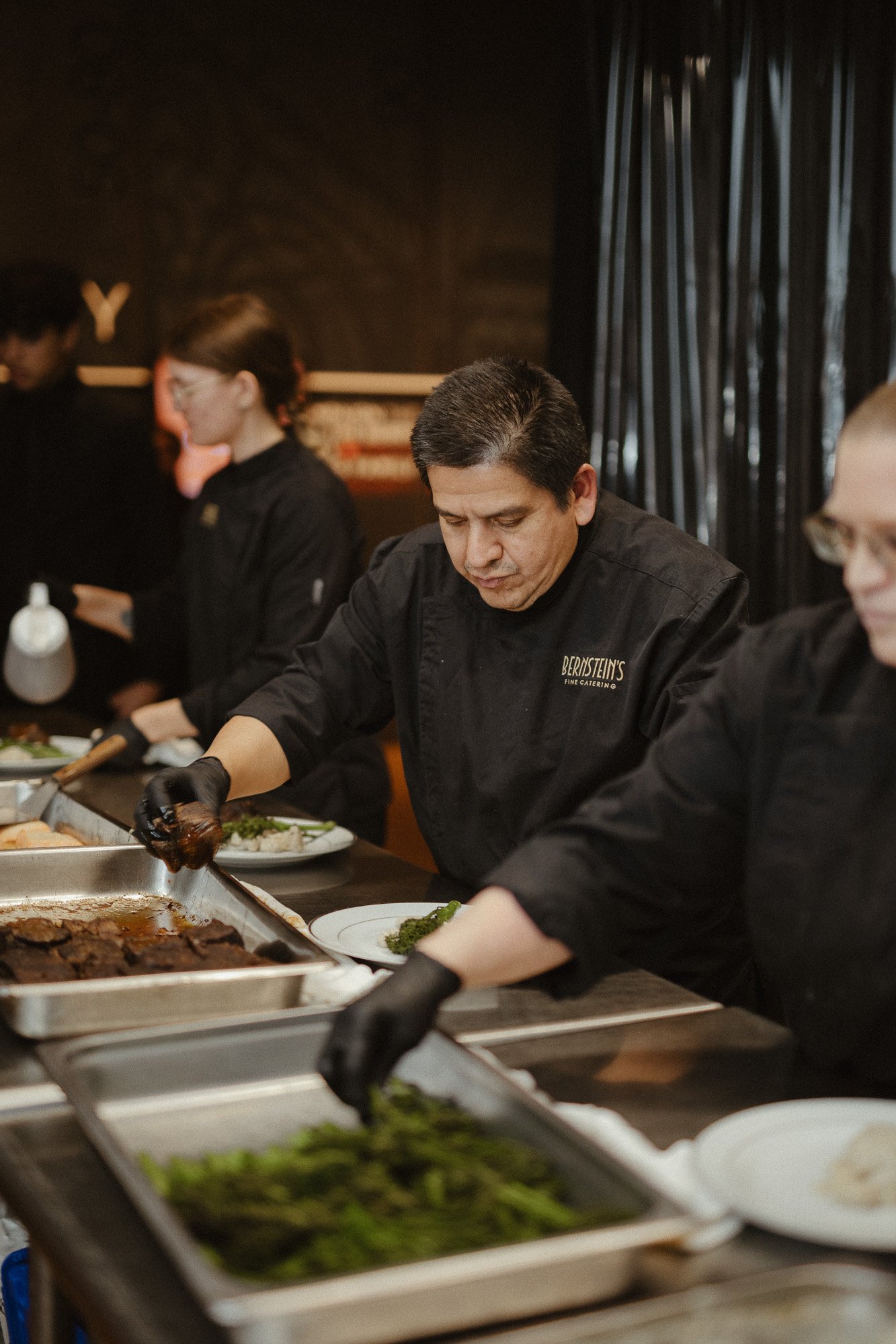 Catering staff prepares food at a buffet table in a restaurant.