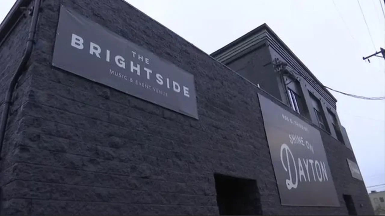 Outdoor view of the brick exterior of a music and event venue called The Brightside with signs on the wall, one that says "The Brightside Music & Event Venue" and another that says "Shine On Dayton."