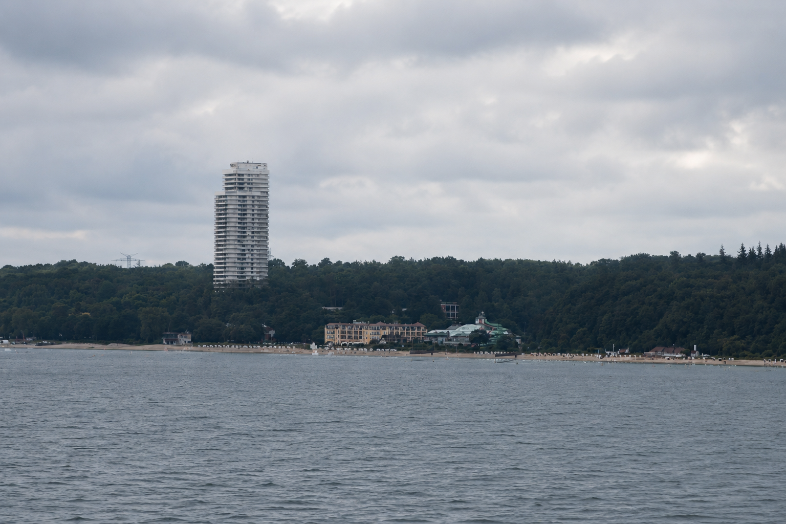 Blick auf einen See mit Stadt und bewölktem Himmel im Hintergrund.