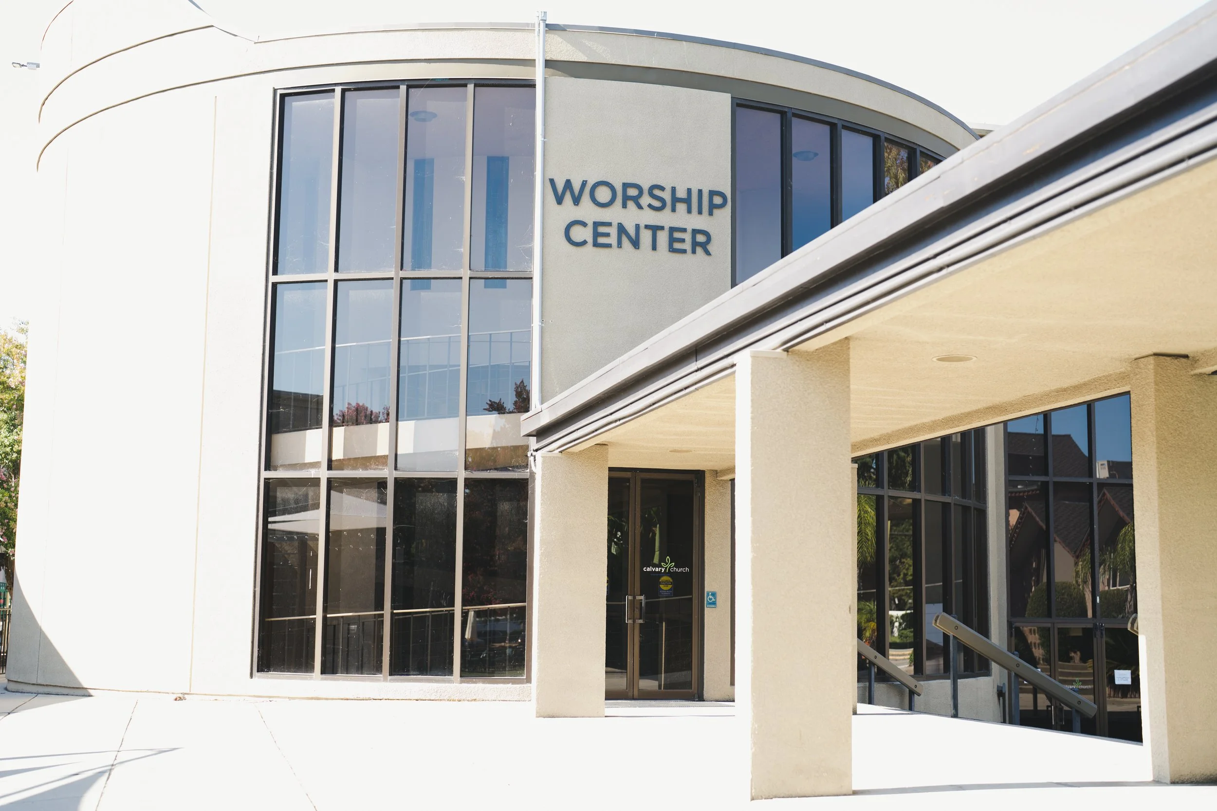 The exterior of a church building with large glass windows and a sign that reads 'WORSHIP CENTER' on the front wall.