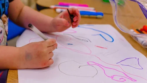 Children drawing colorful shapes and lines on paper.