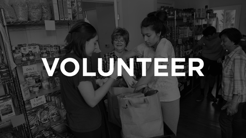 Group of people volunteering at a food bank, packing food into bags.