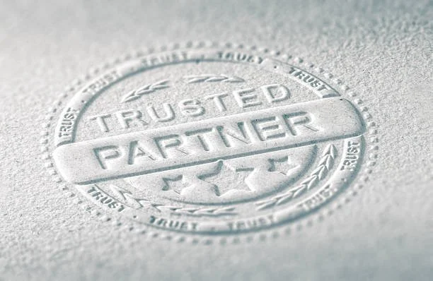 Close-up of a silver embossed seal reading "Trusted Partner" on textured paper.