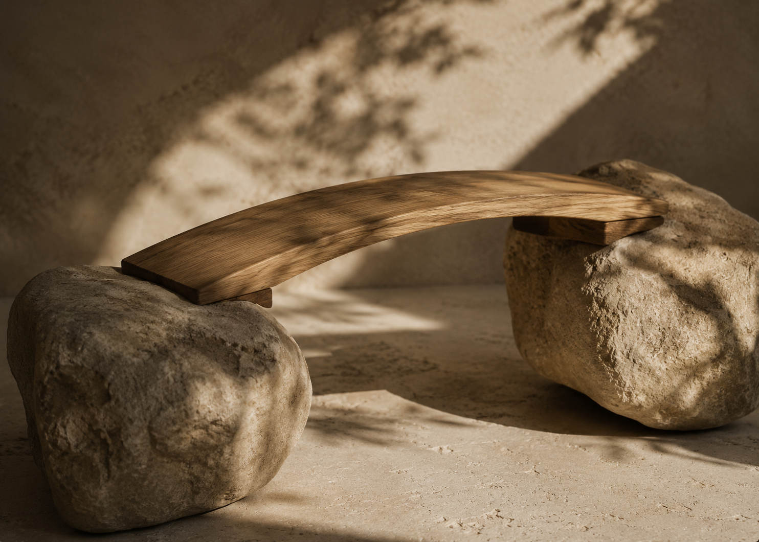 A minimalist wooden bridge placed across two large rocks, with sunlight casting shadows on a sandy surface.