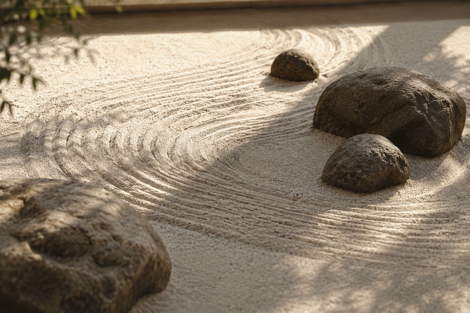 Zen garden with raked sand and four large rocks arranged in the sand.