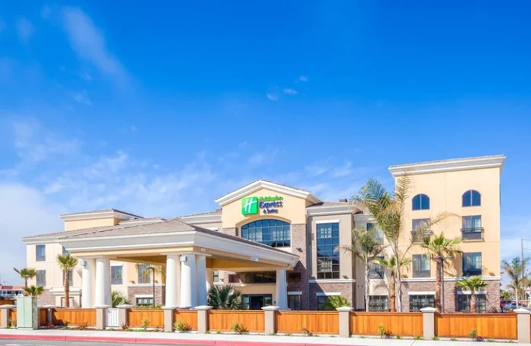 Exterior of a Holiday Inn Express hotel with palm trees and a clear blue sky.