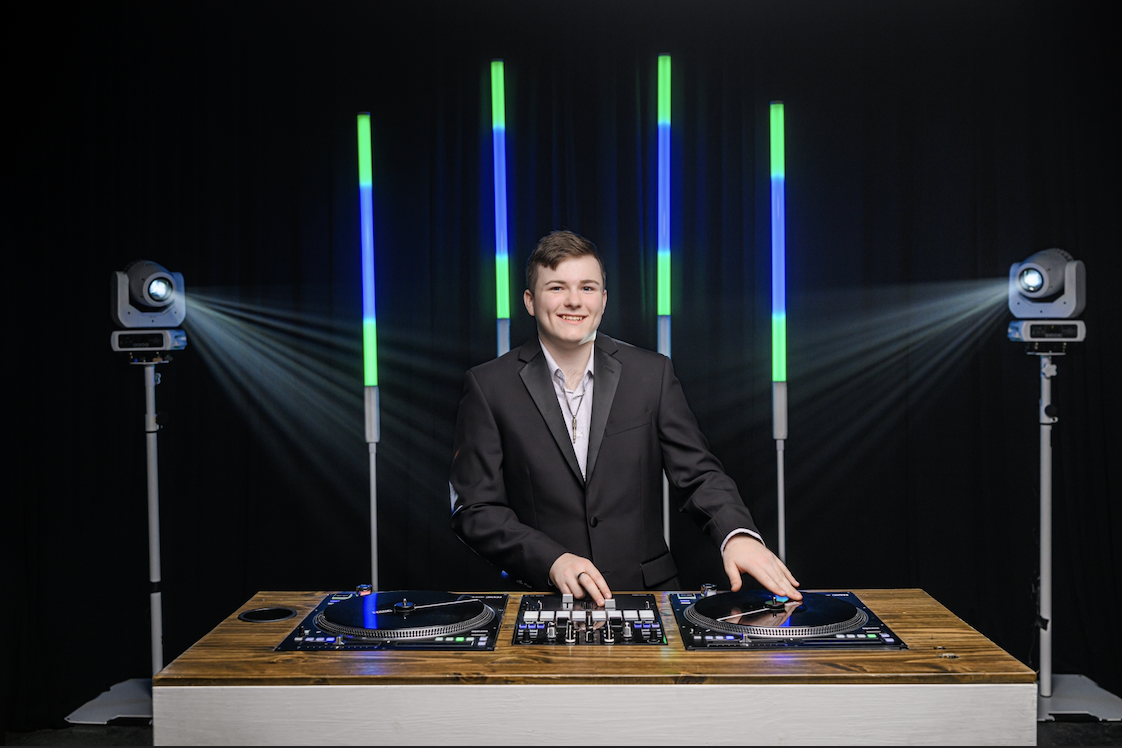DJ Hauser mixing on turntables with LED tube lighting behind him