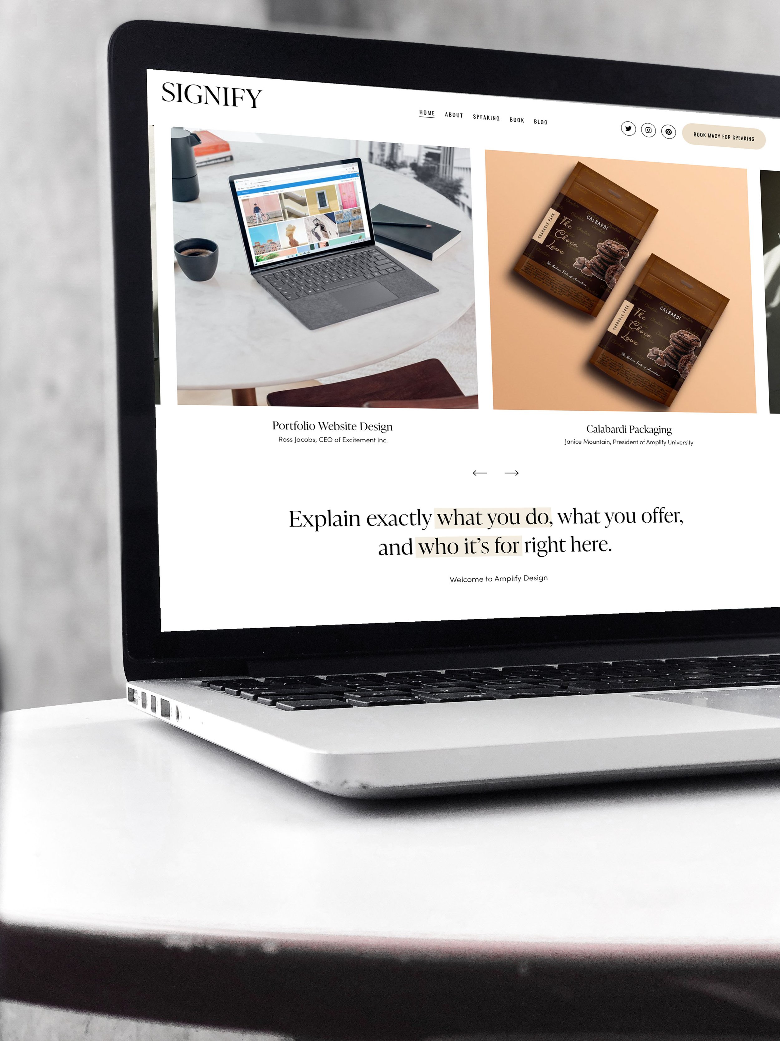 A laptop on a white table displaying a website with the title 'Portfolio Website Design' and images of various design projects.