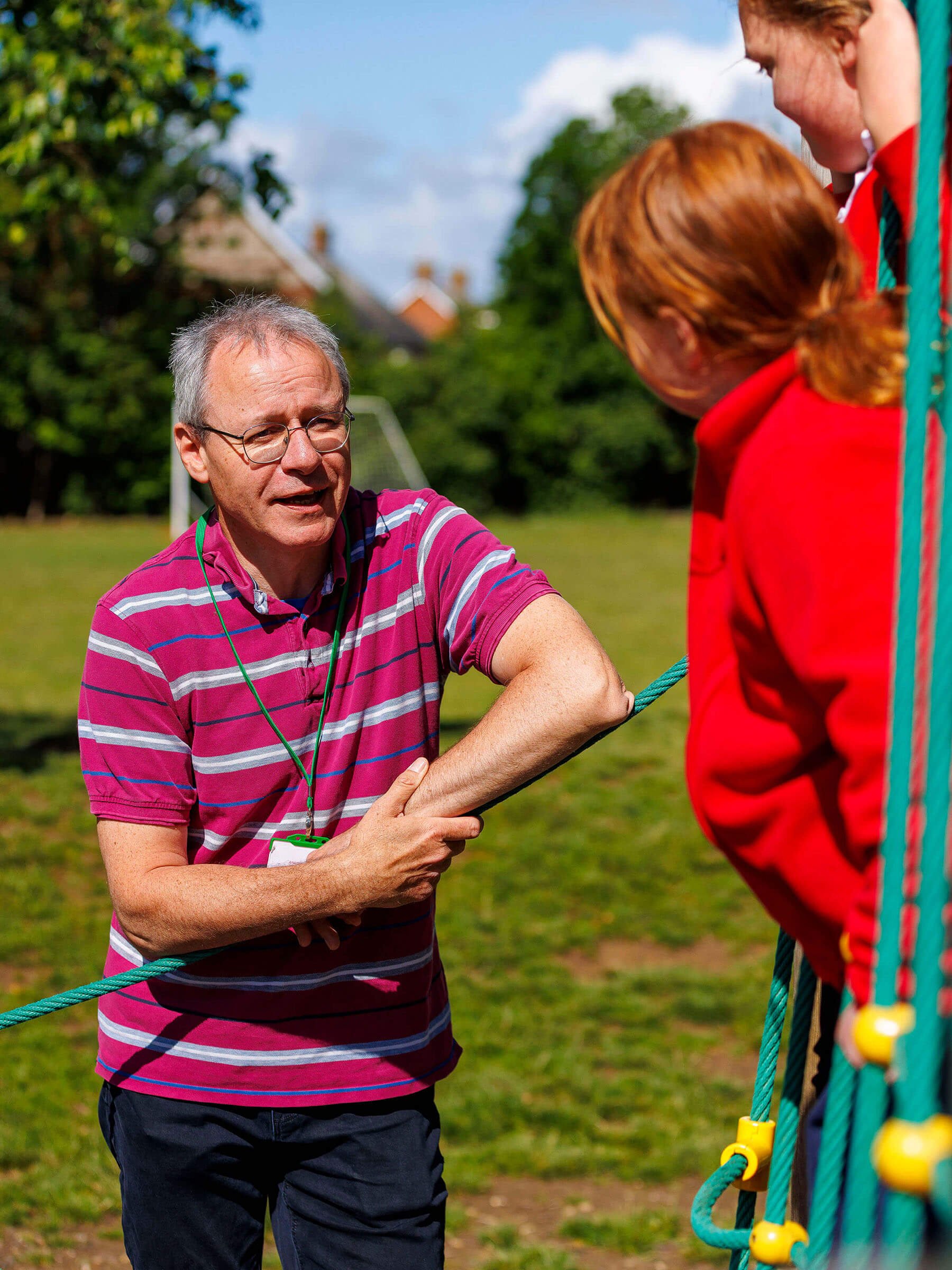 A Bridge Project chaplain talking with 2 children in a school playground.