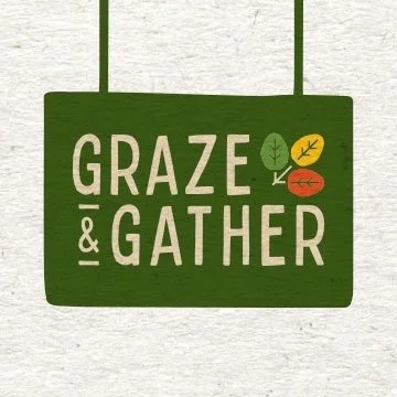 A green sign hanging from two strings with the words 'GRAZE & GATHER' and three colored leaves in yellow, red, and green.