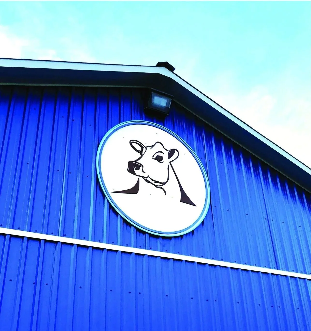Blue building  featuring the Sargent Family Dairy logo an illustration of a cow's head.