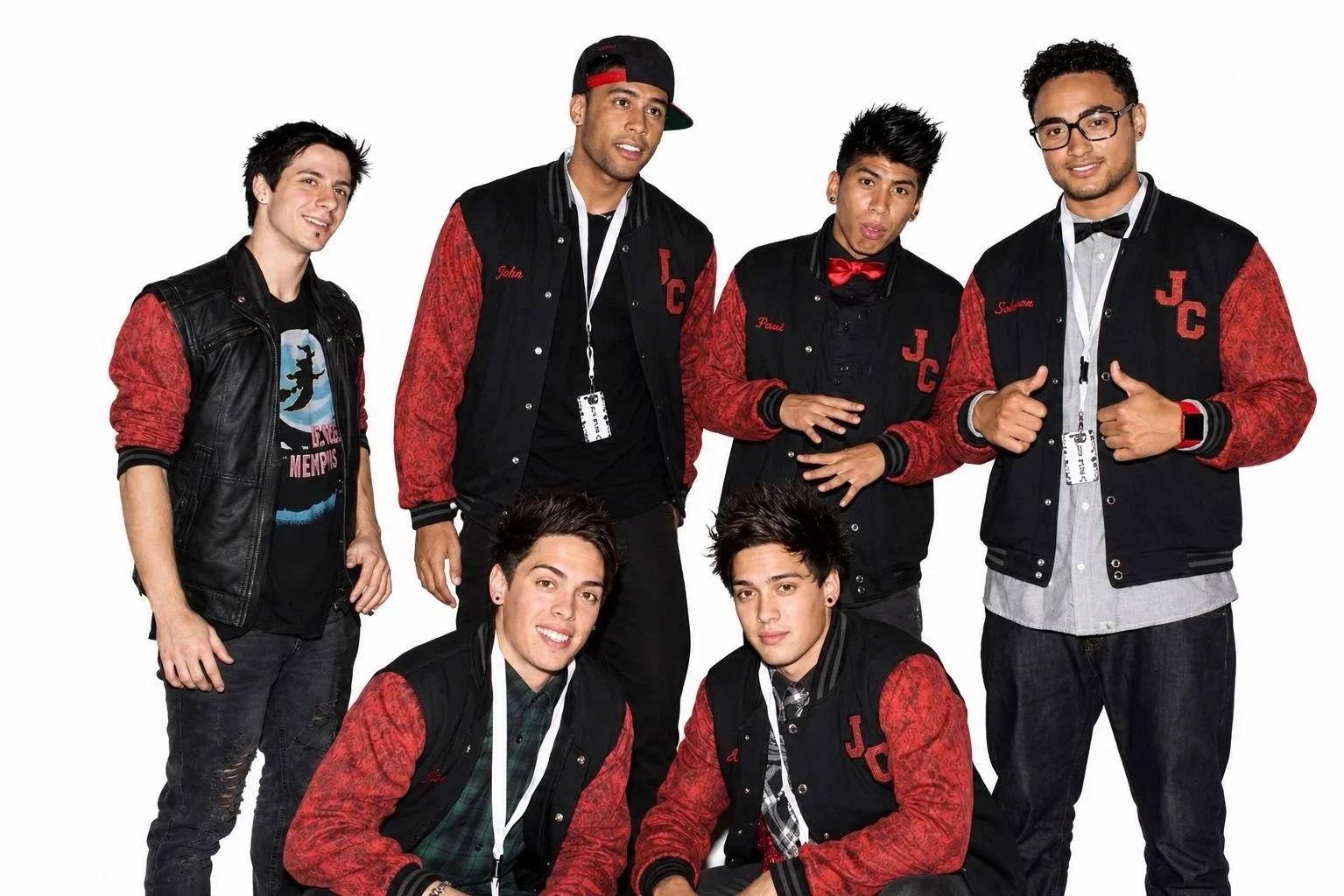 Group of six young men wearing casual and varsity jackets, some with name badges, posing together against a plain white background.