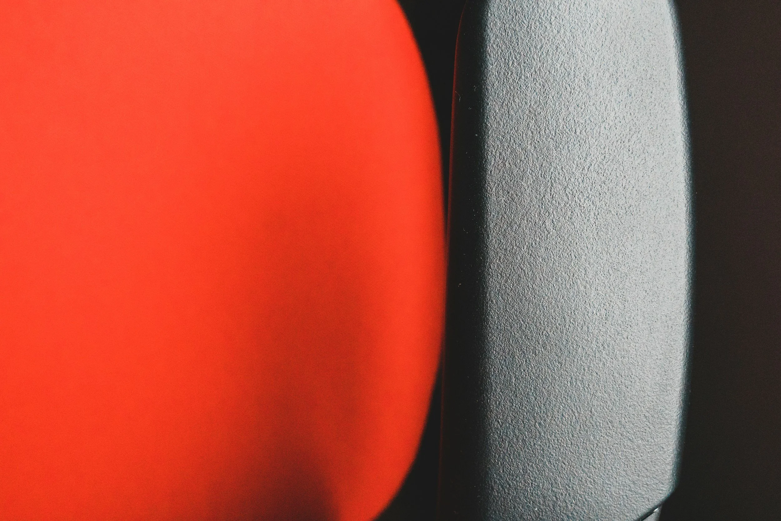 Close-up of three rounded objects with different textures and colors: one orange, one black, and one gray, positioned closely together.