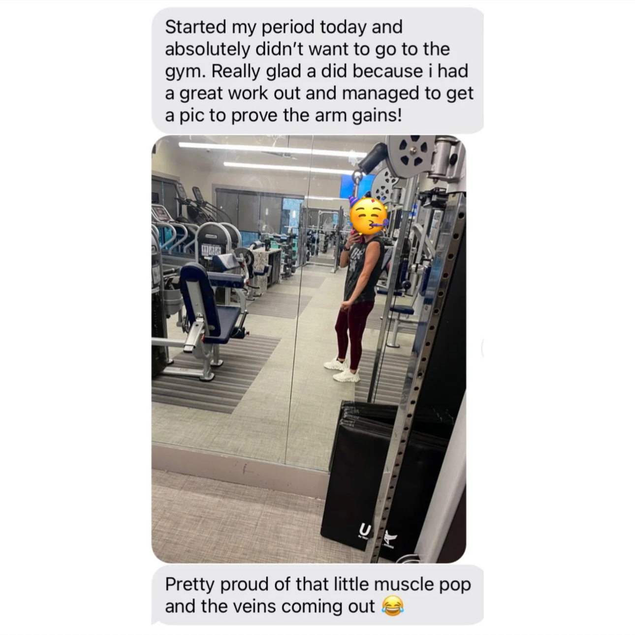 A woman taking a mirror selfie in a gym, wearing workout clothes, while a pride emoji with a party hat and wig covers her face. The gym has various exercise equipment, including weight machines and cardio equipment, with a reflective wall and carpete