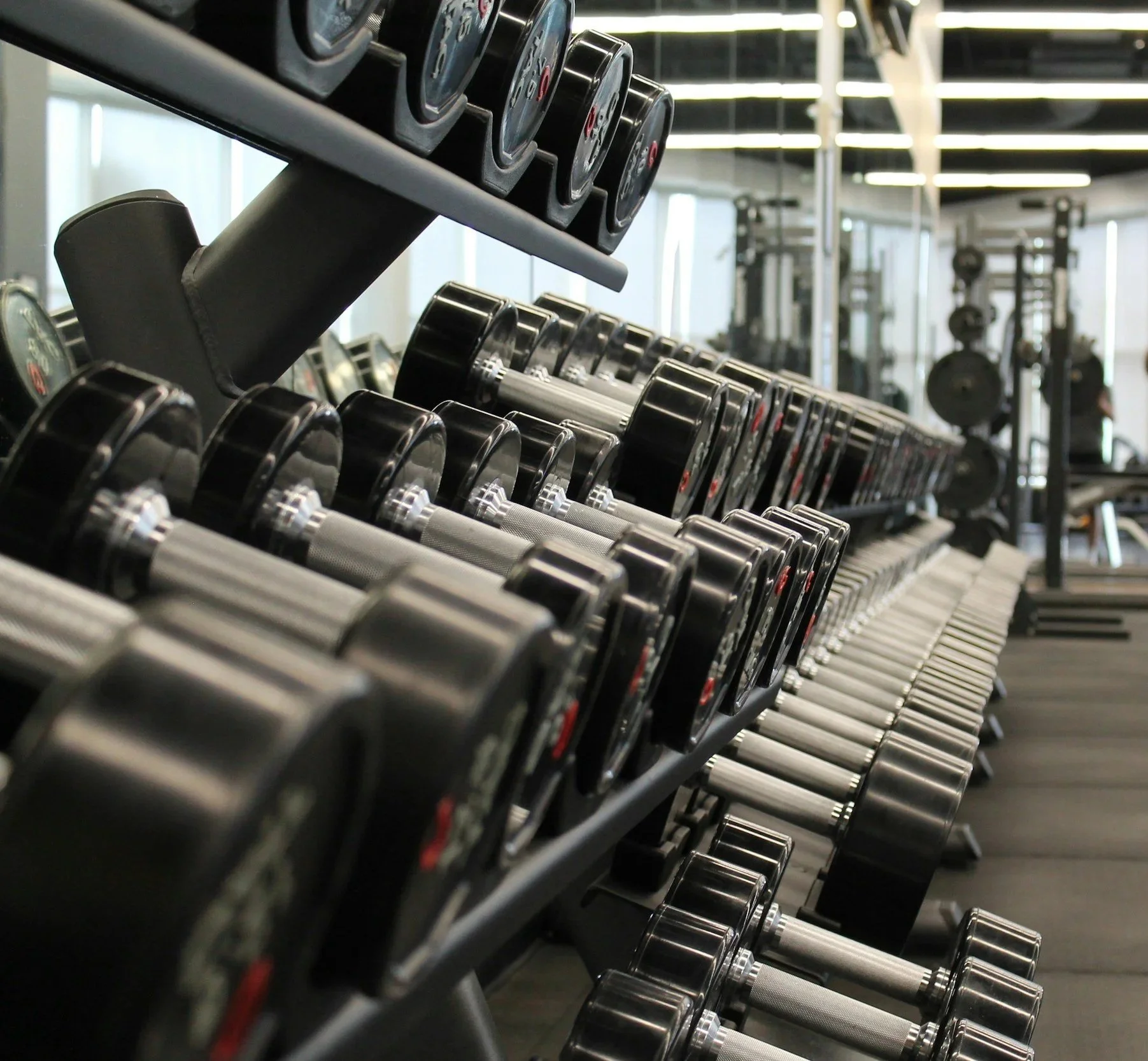 Multiple black and silver dumbbells arranged on a rack in a gym.