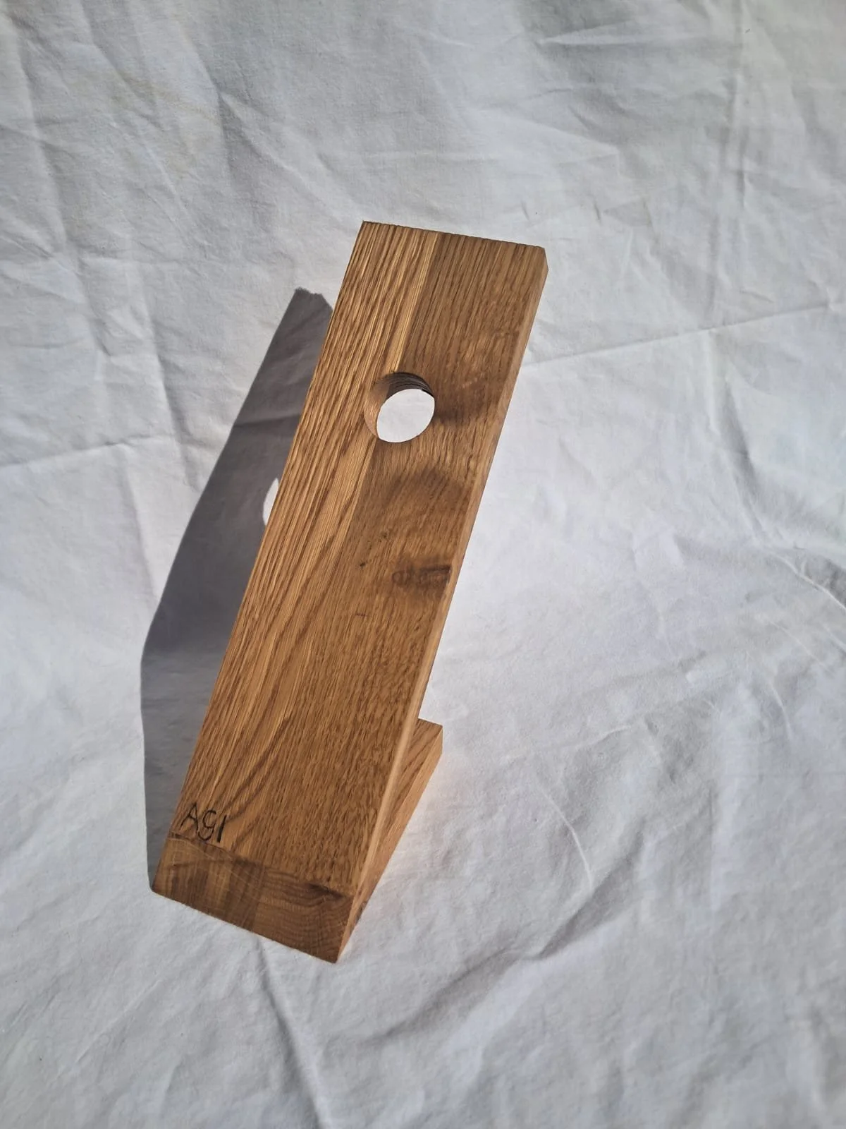 Ein Holzstück mit runden Löchern, das auf einem weißen, vermutlich Papiertuch liegt.