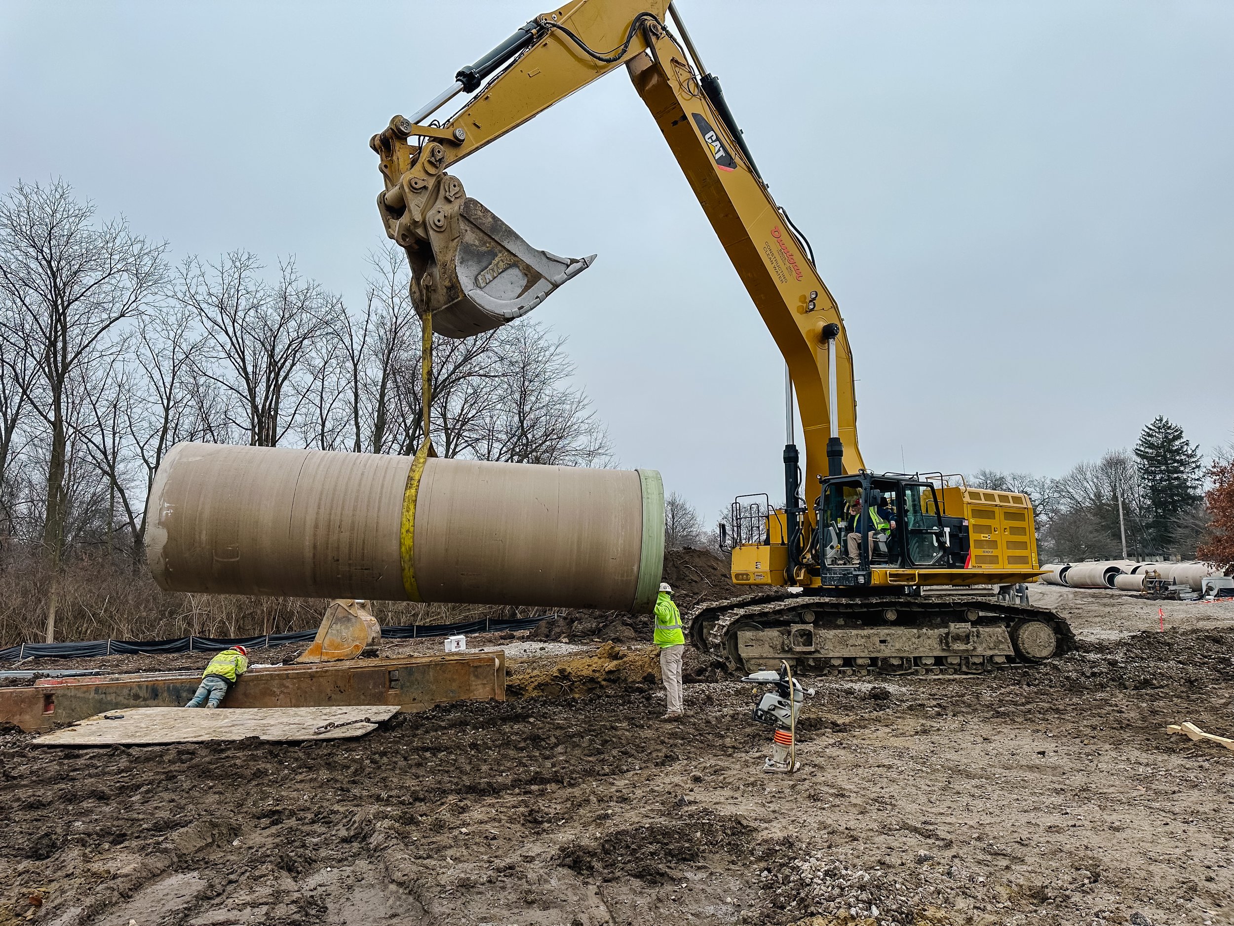 Dunigan Bros. excavator lifting large diameter pipe on an underground utility project