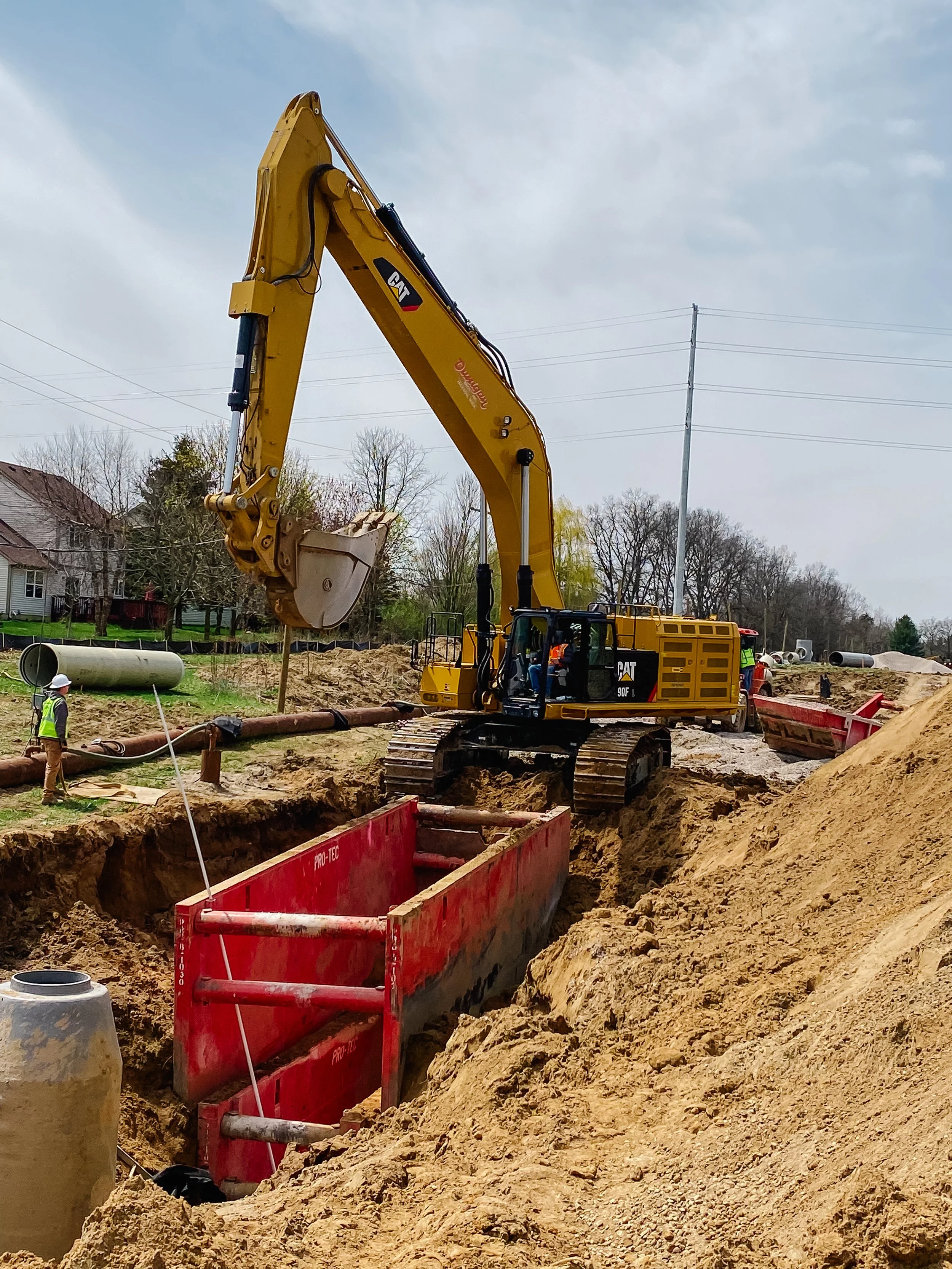 Dunigan Bros. excavator digging an open cut trench on an underground utility project in a residential area