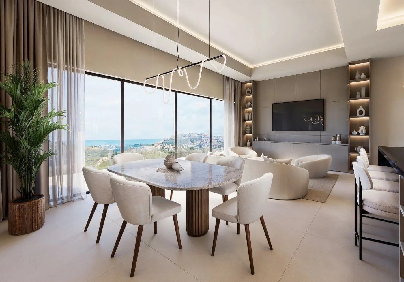 Modern living room with large windows showing ocean view, white furniture, a round dining table, built-in shelves with decor, and a wall-mounted TV.
